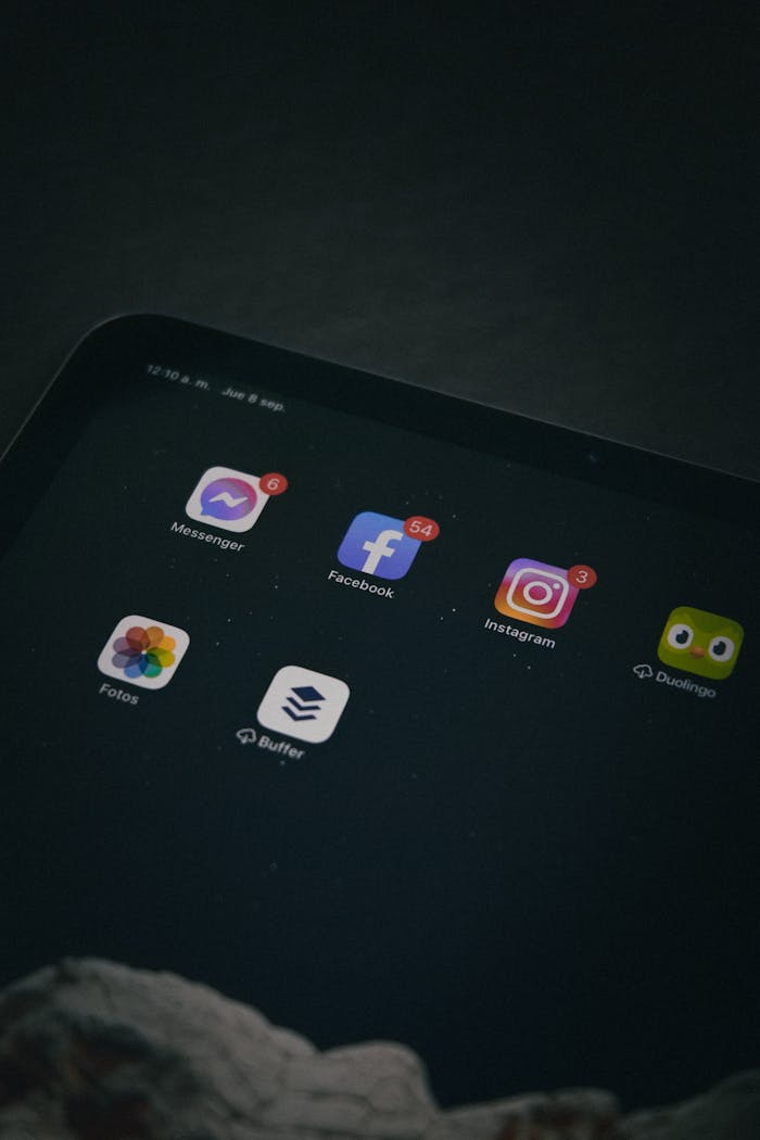 Close-up of a tablet screen displaying social media apps in a dim setting.